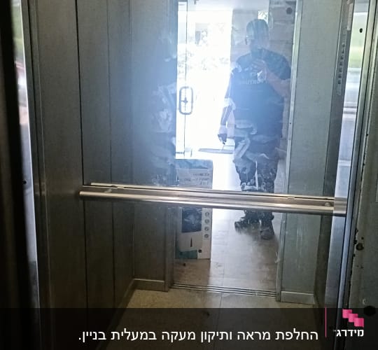 מעלית עם דלתות זכוכית ואדם משתקף